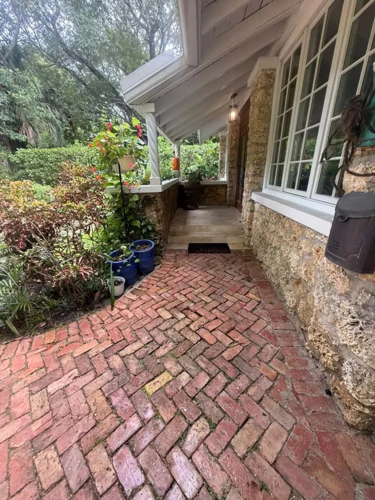 Brick walkway along a coral stone home before cleaning