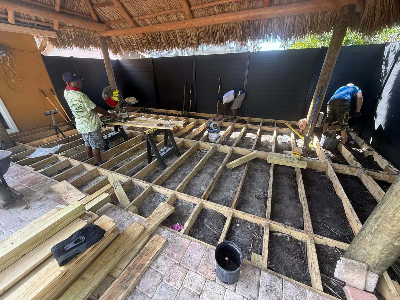 Crew framing a wood deck under a tiki hut