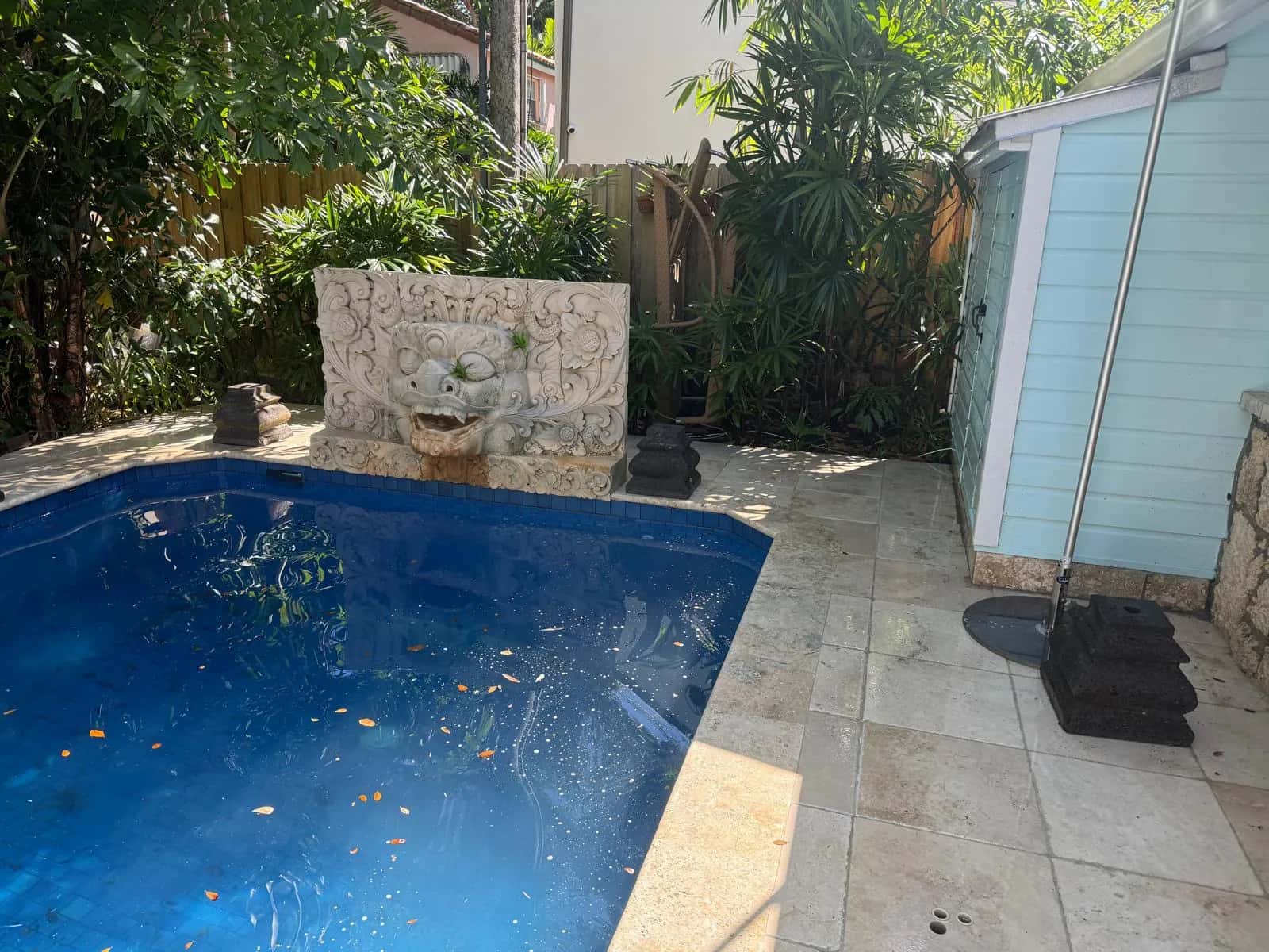 Small pool with clean stone deck and fountain wall after cleaning