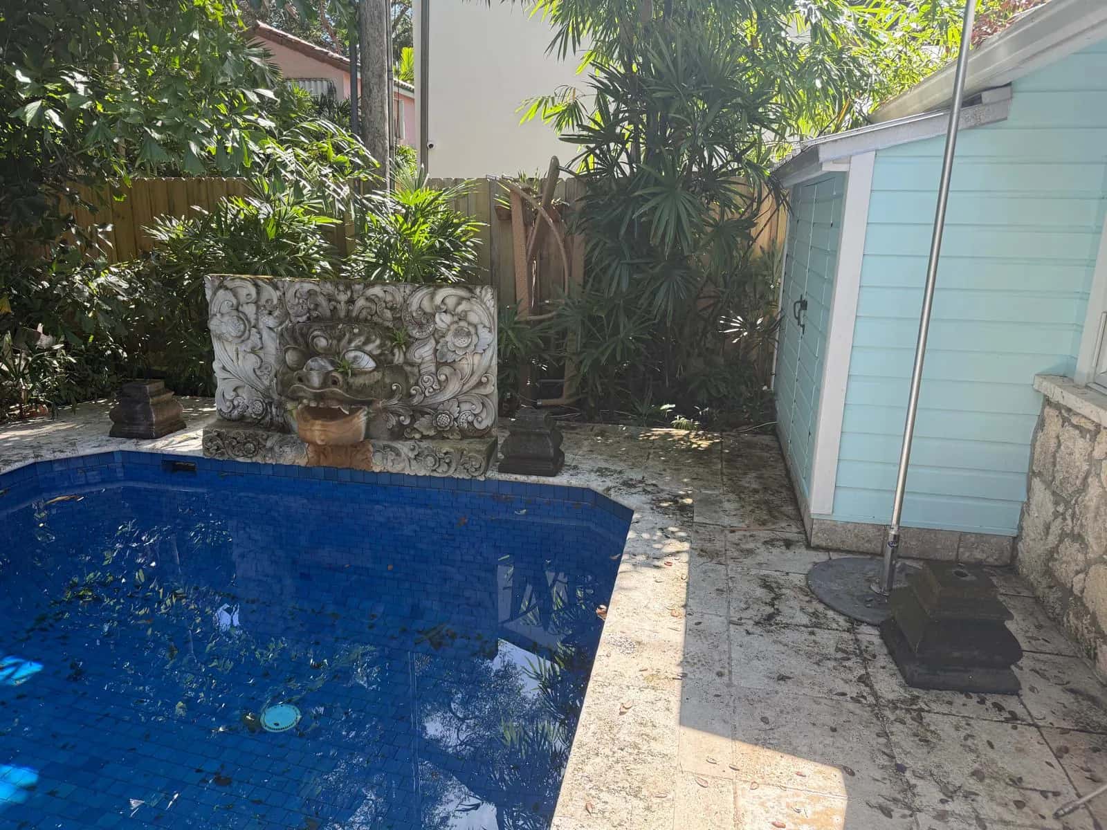 Small pool and stone deck covered in grime before cleaning