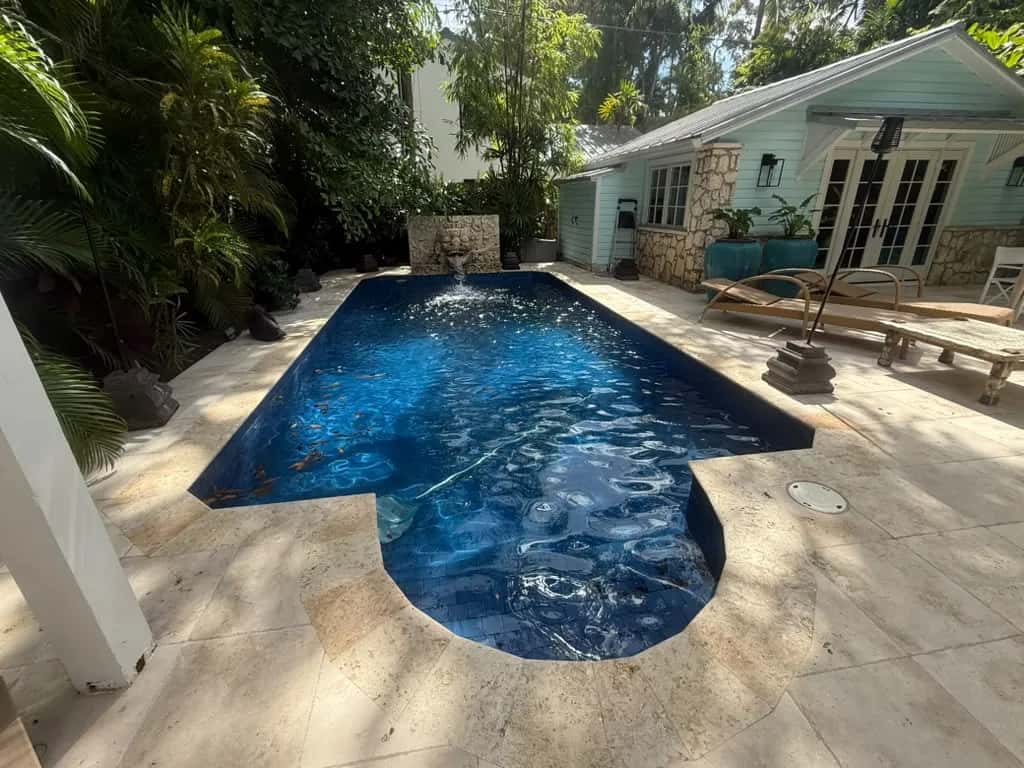 Clean travertine pool deck and blue tile pool after cleaning