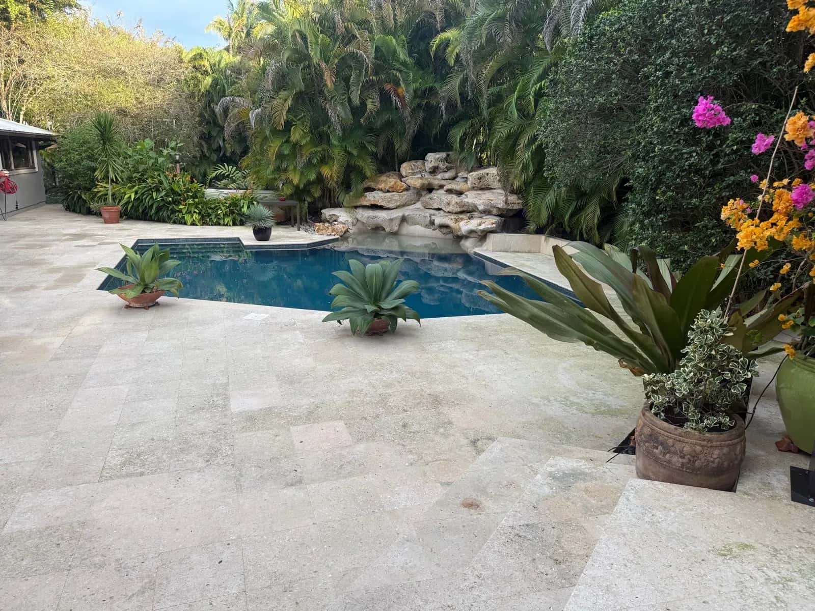 Bright travertine deck and rock waterfall pool after cleaning