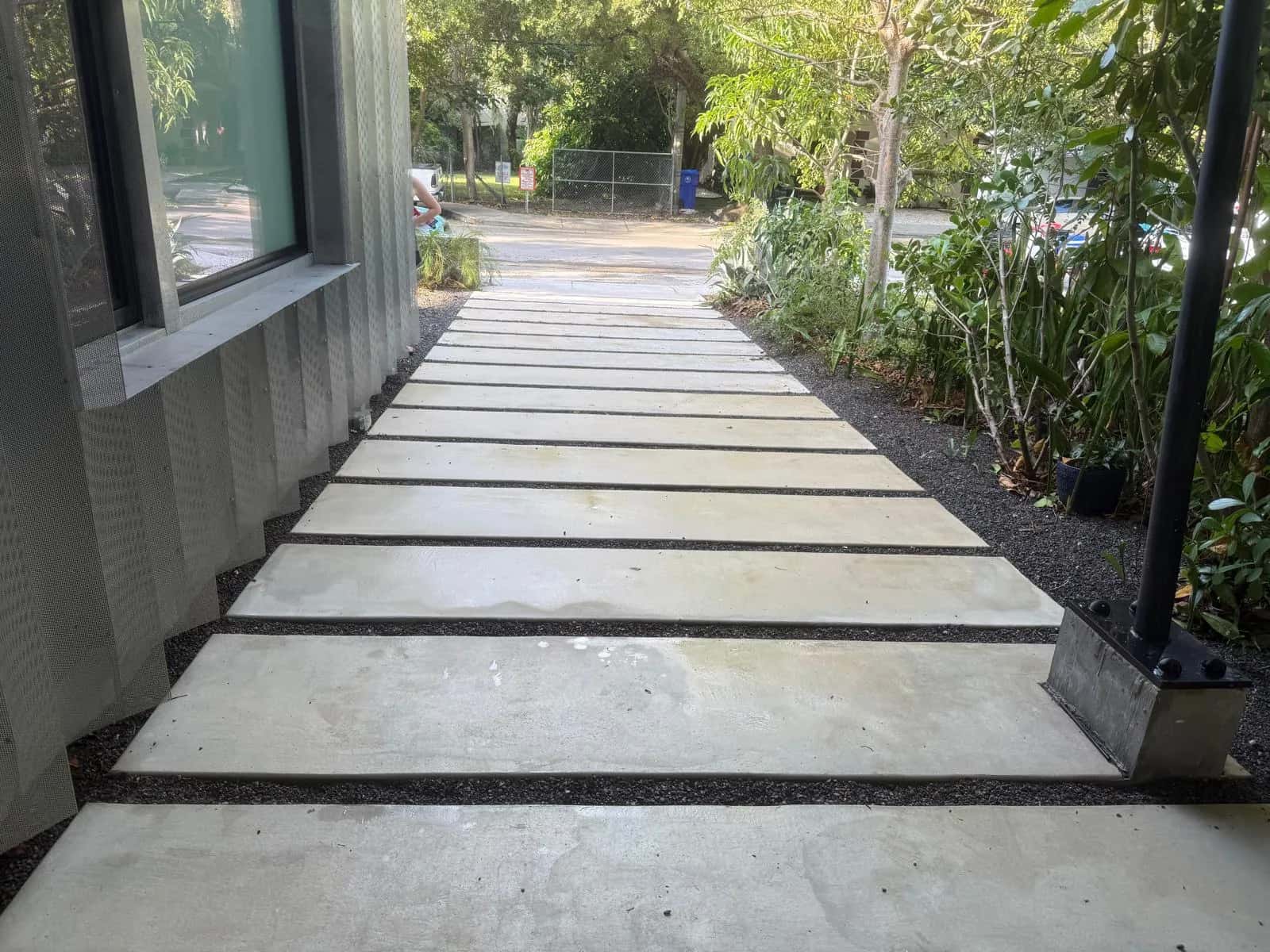 Modern concrete slab walkway with black gravel joints after cleaning