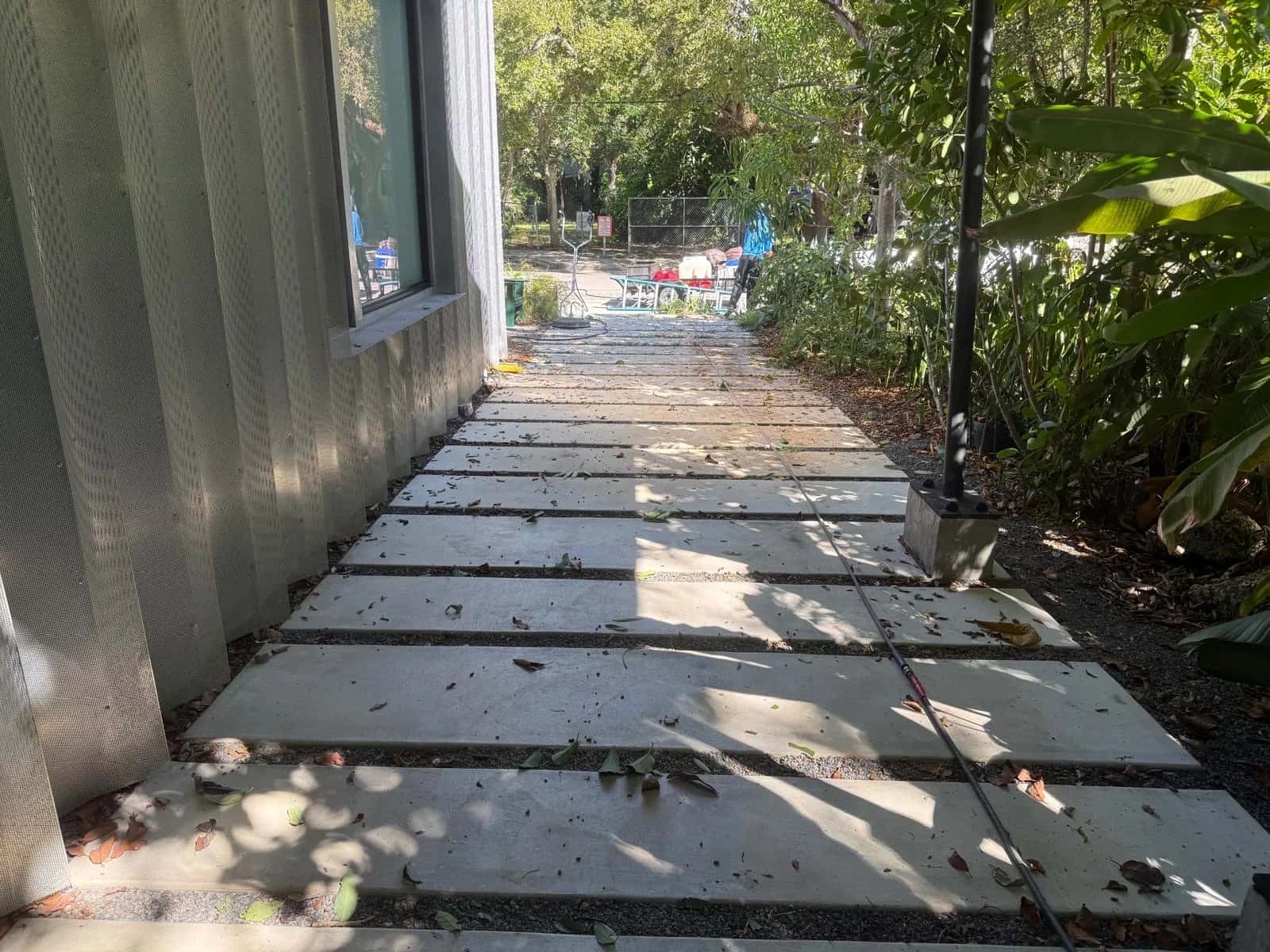 Concrete slab walkway covered in debris before cleaning