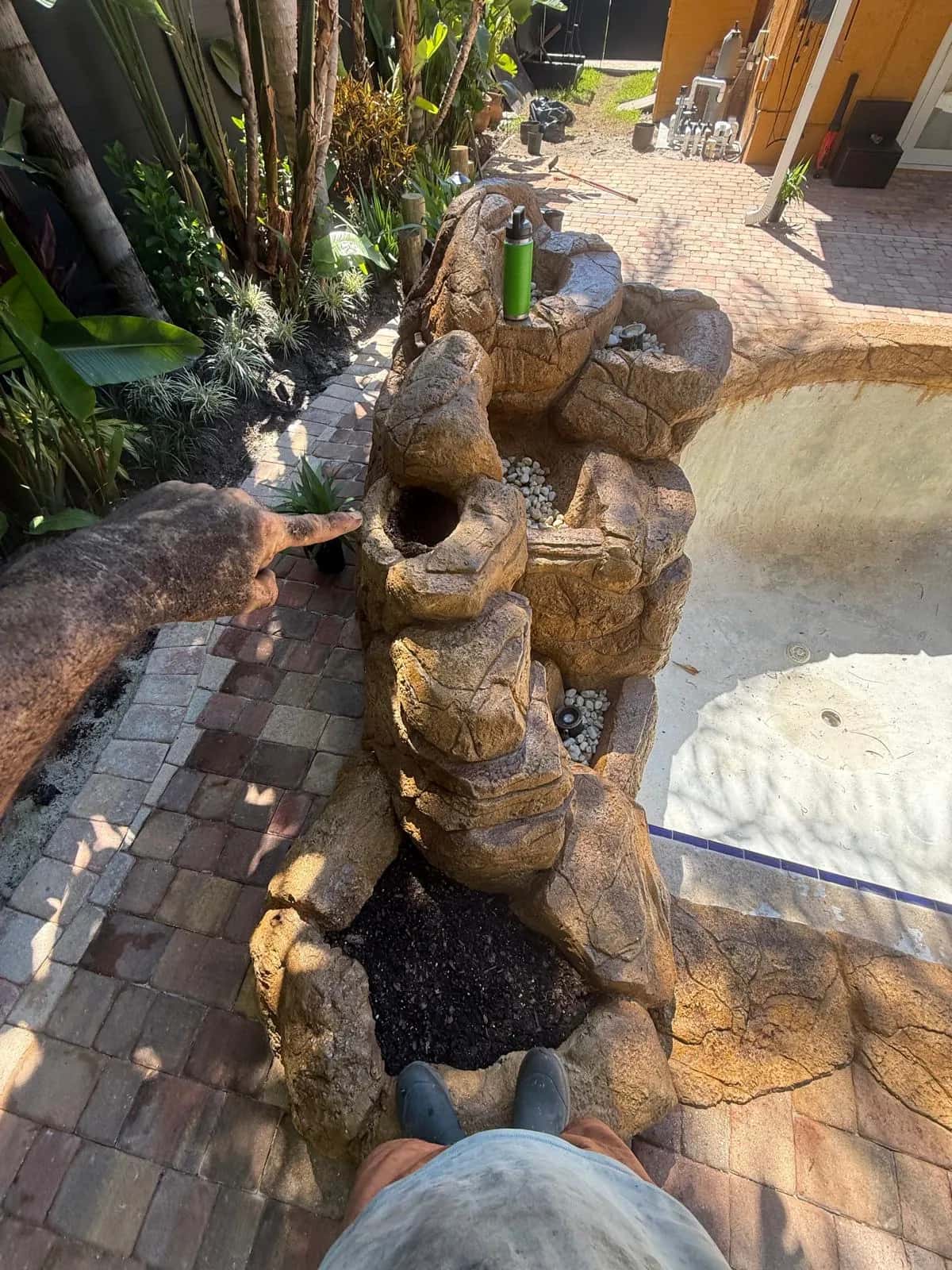 Rock waterfall and planter beside a paver pool deck