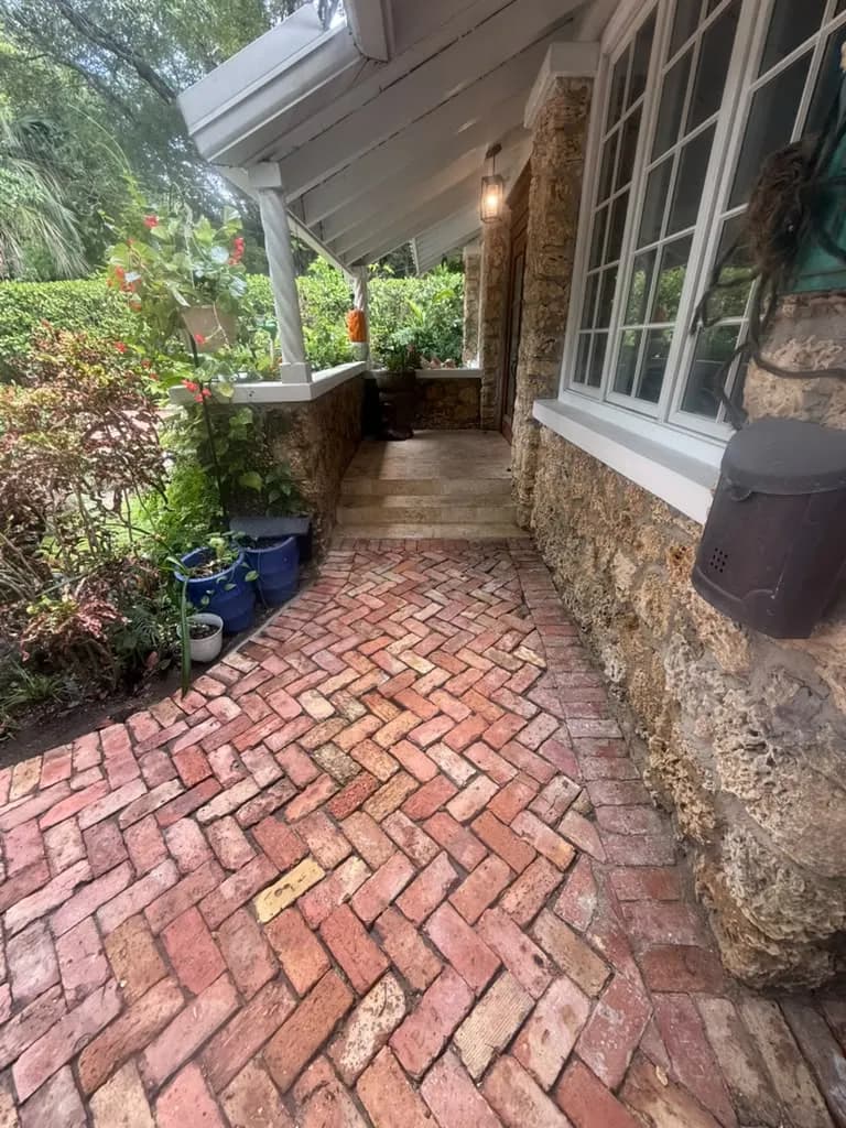 Brick walkway along a coral stone home after cleaning — Looking New, serving Hallandale Beach