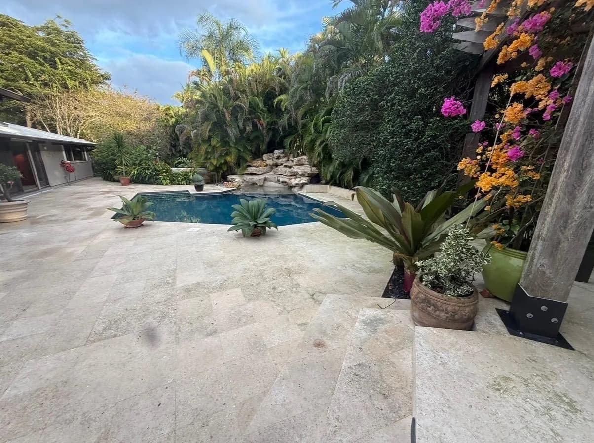 Travertine pool deck with rock waterfall after pressure cleaning — Looking New, serving Coconut Creek