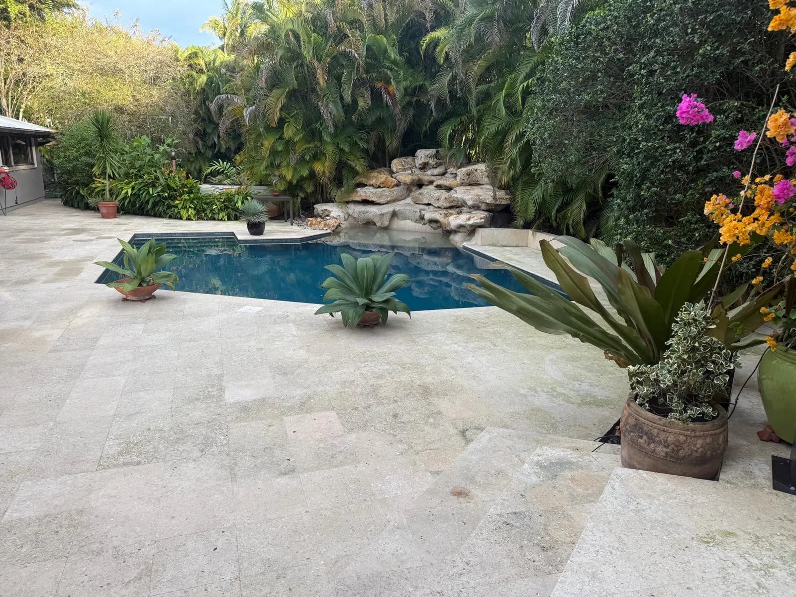 Bright travertine deck and rock waterfall pool after cleaning — Looking New, serving Deerfield Beach