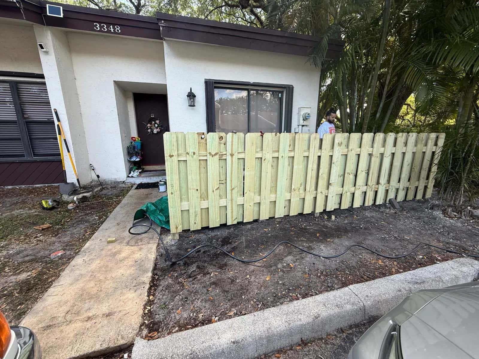 New unpainted wood fence in front of a townhome