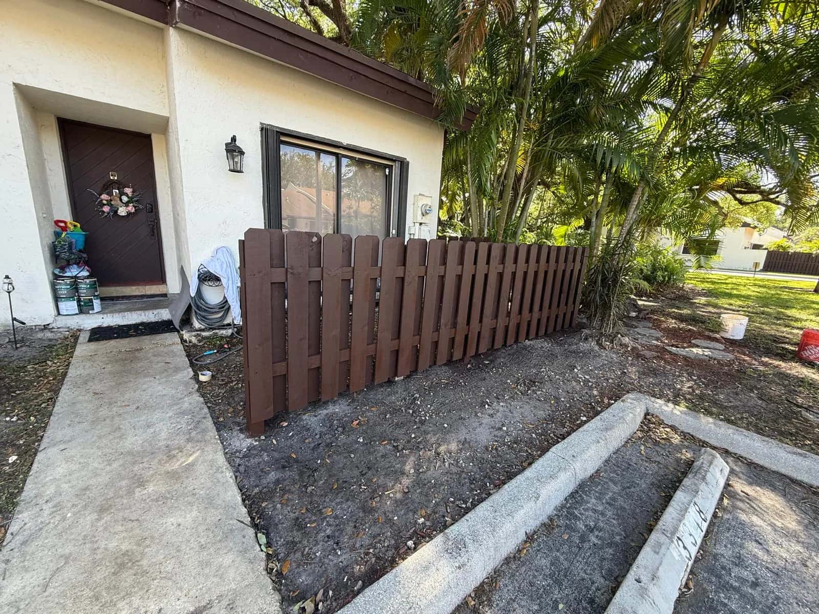 New wood fence painted dark brown in front of a townhome