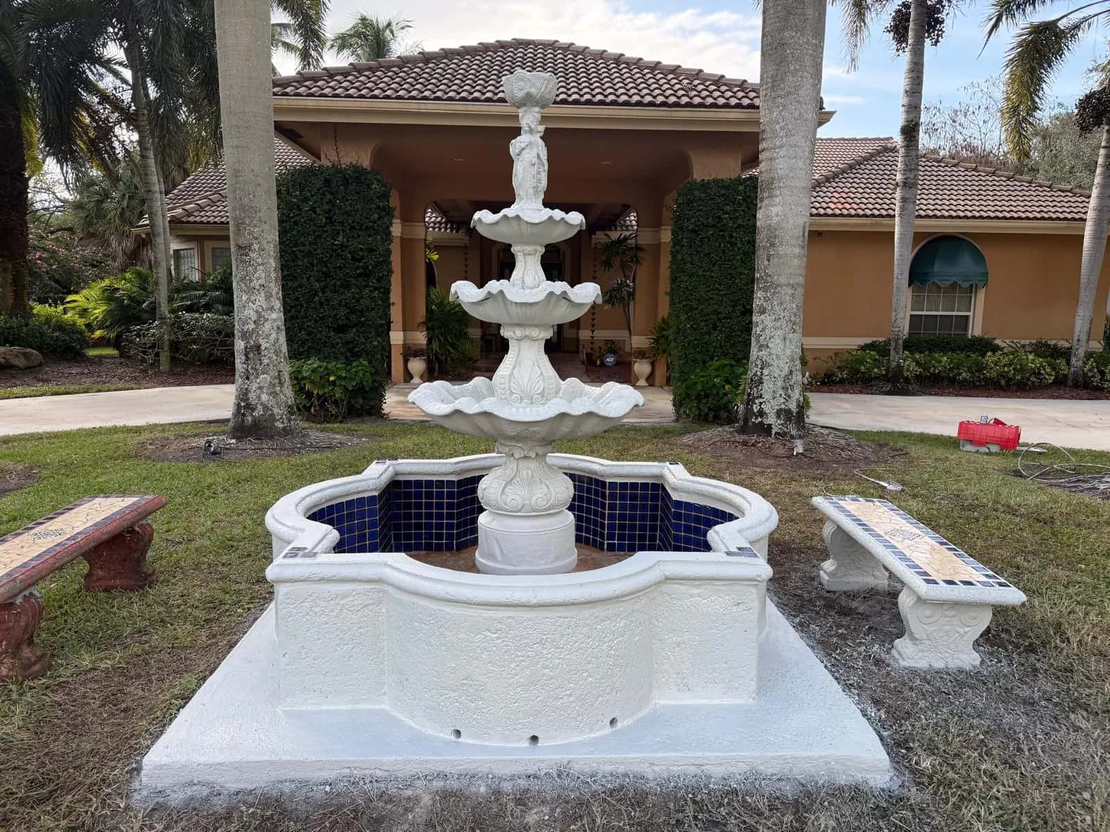 Tiered fountain repainted white with blue tile after restoration